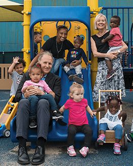 Movida Heights Leadership smiling with children in playground
